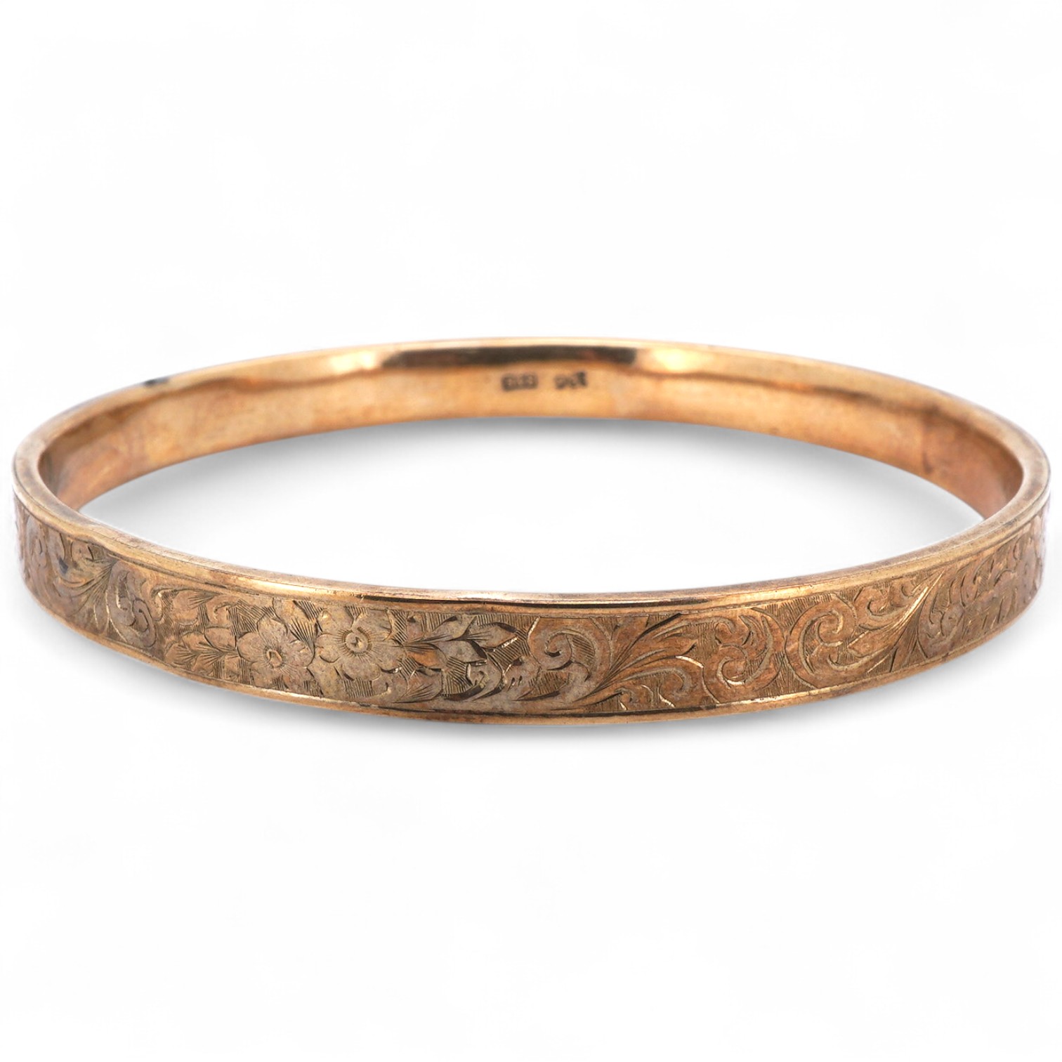 A gold bangle, engraved with scrolled decoration, inner circumference approximately 21.5cm, stamped 9CT, gross weight approximately 10 grams